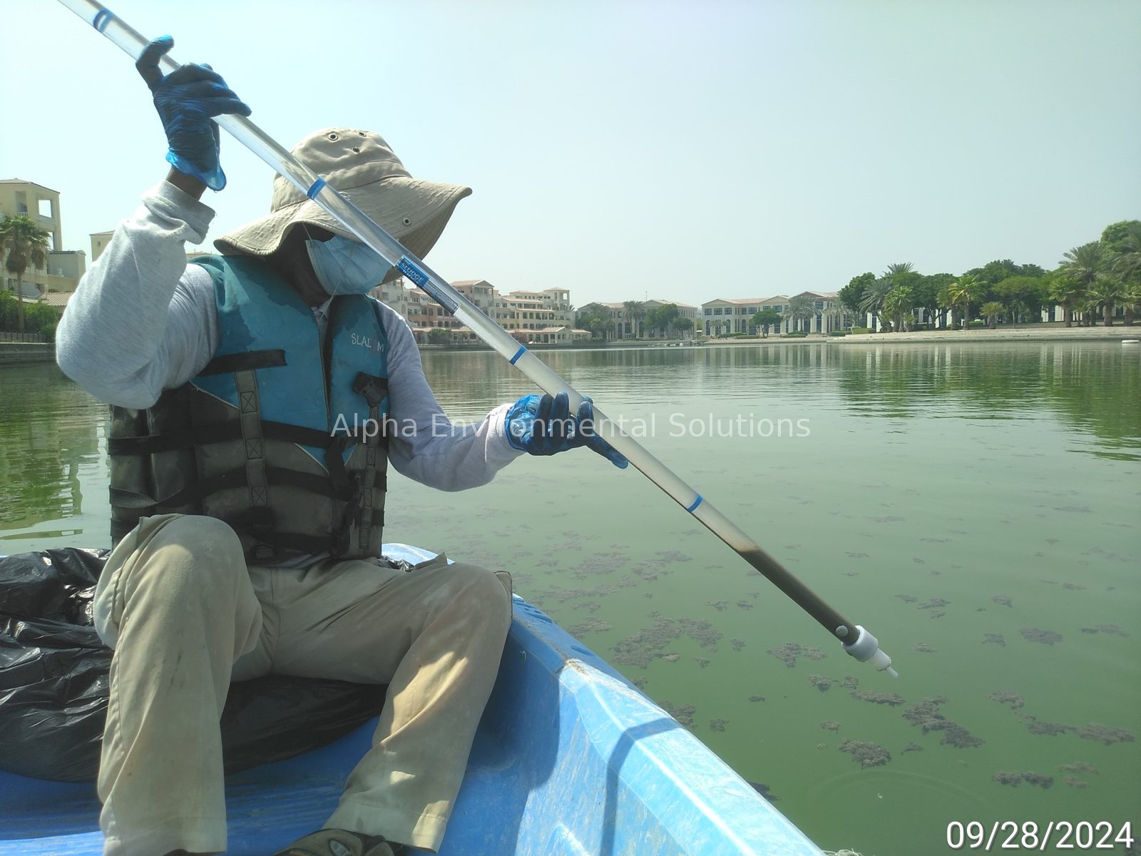 Alpha Environmental Solutions technician profiling sludge depth with a sludge probe on a Dubai community lake