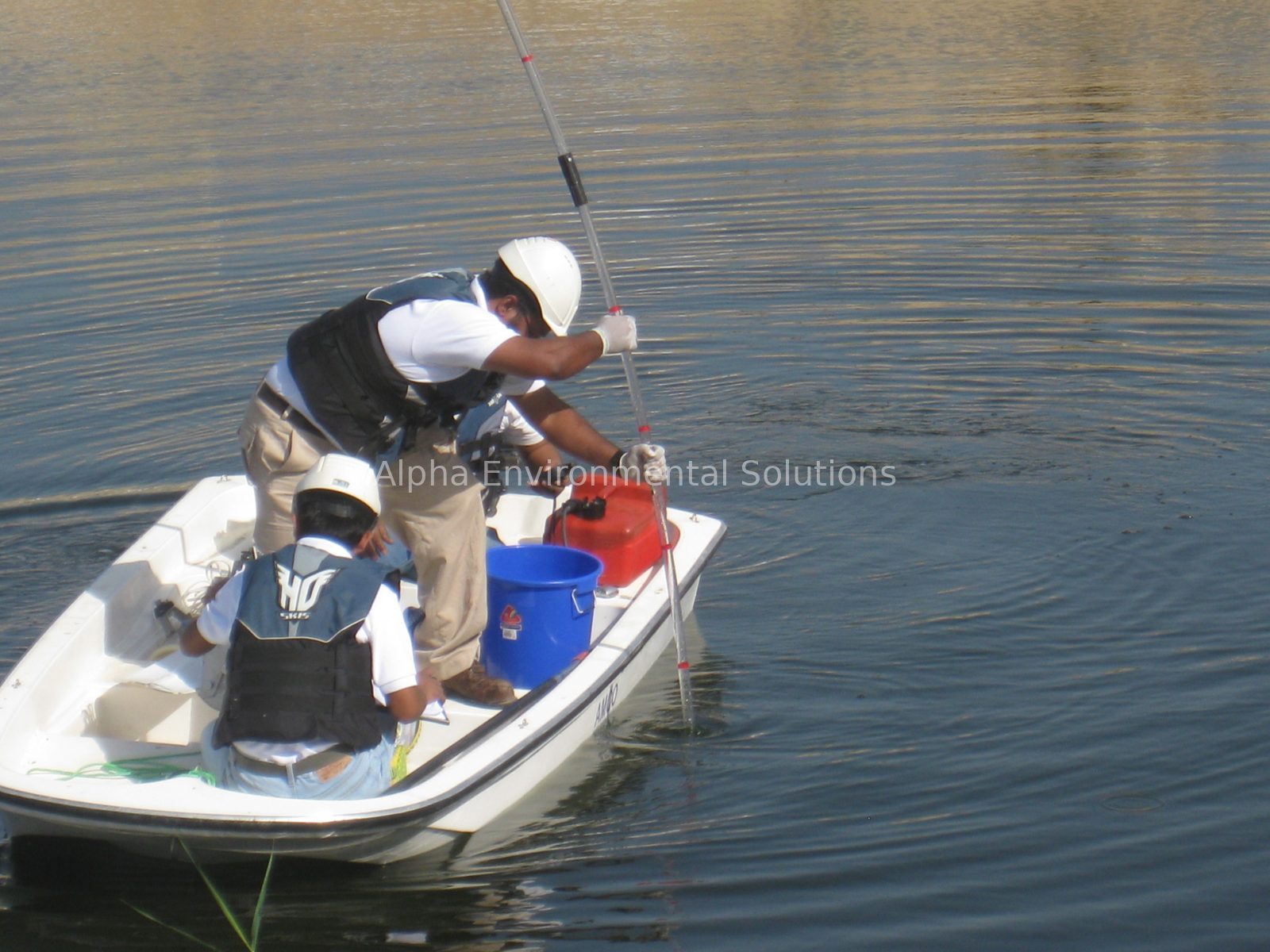 Alpha Environmental Solutions technicians measuring sludge depth from a boat on a UAE community lake