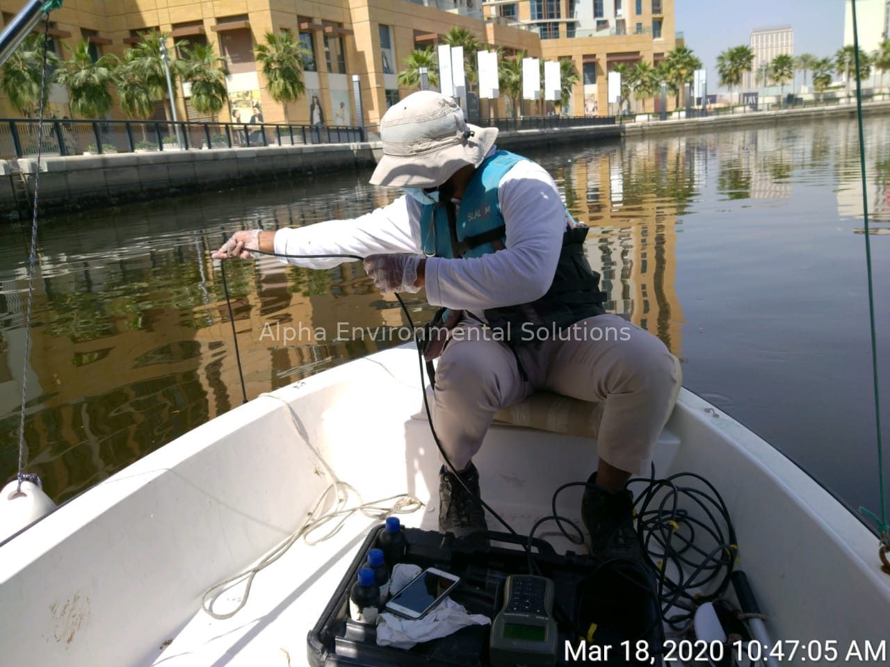 Technician on a small boat measuring lake water quality with a probe and meter on a Middle East canal